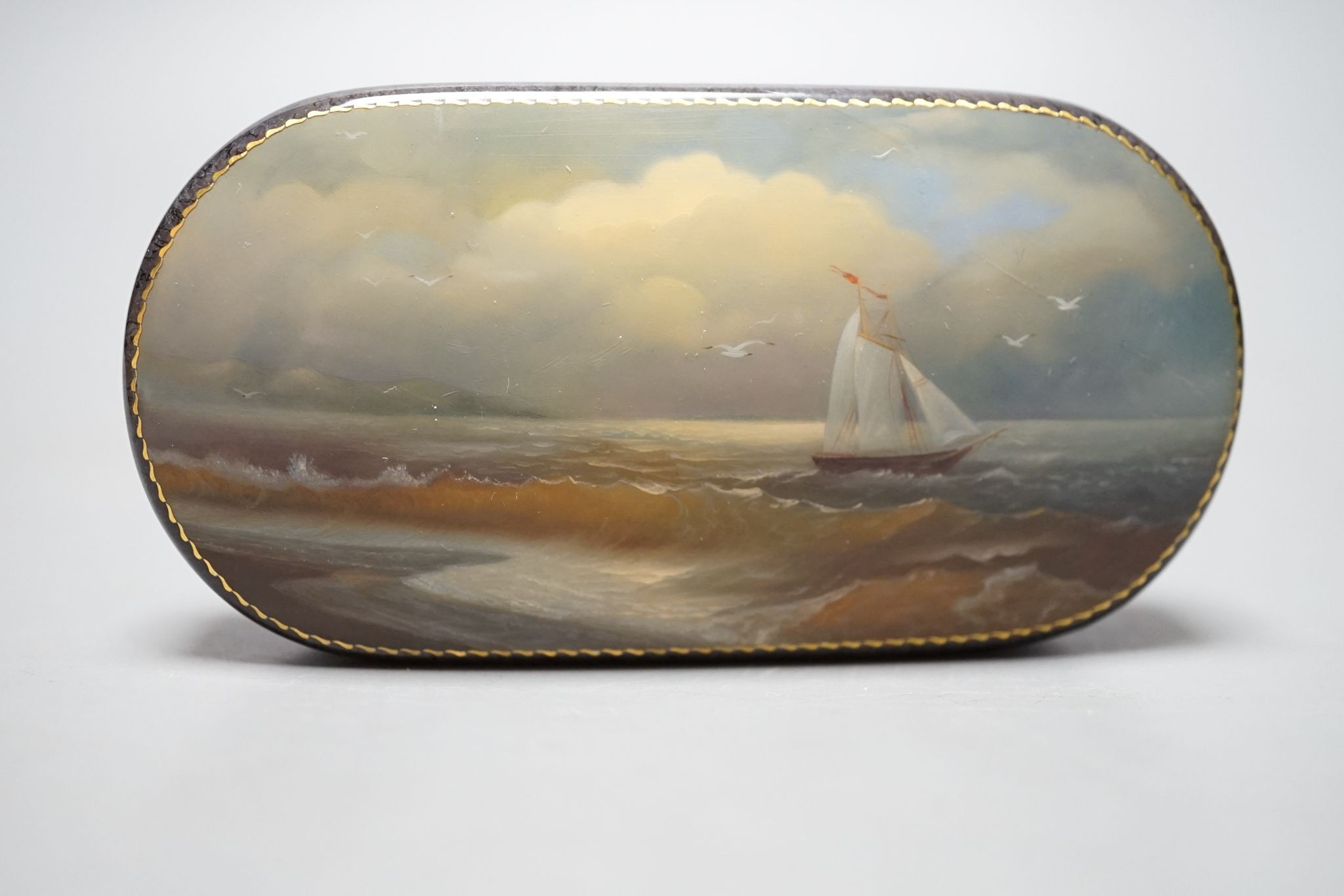 A Russian oval lacquered box, 10cm., and a porcelain box painted with ships approaching harbour